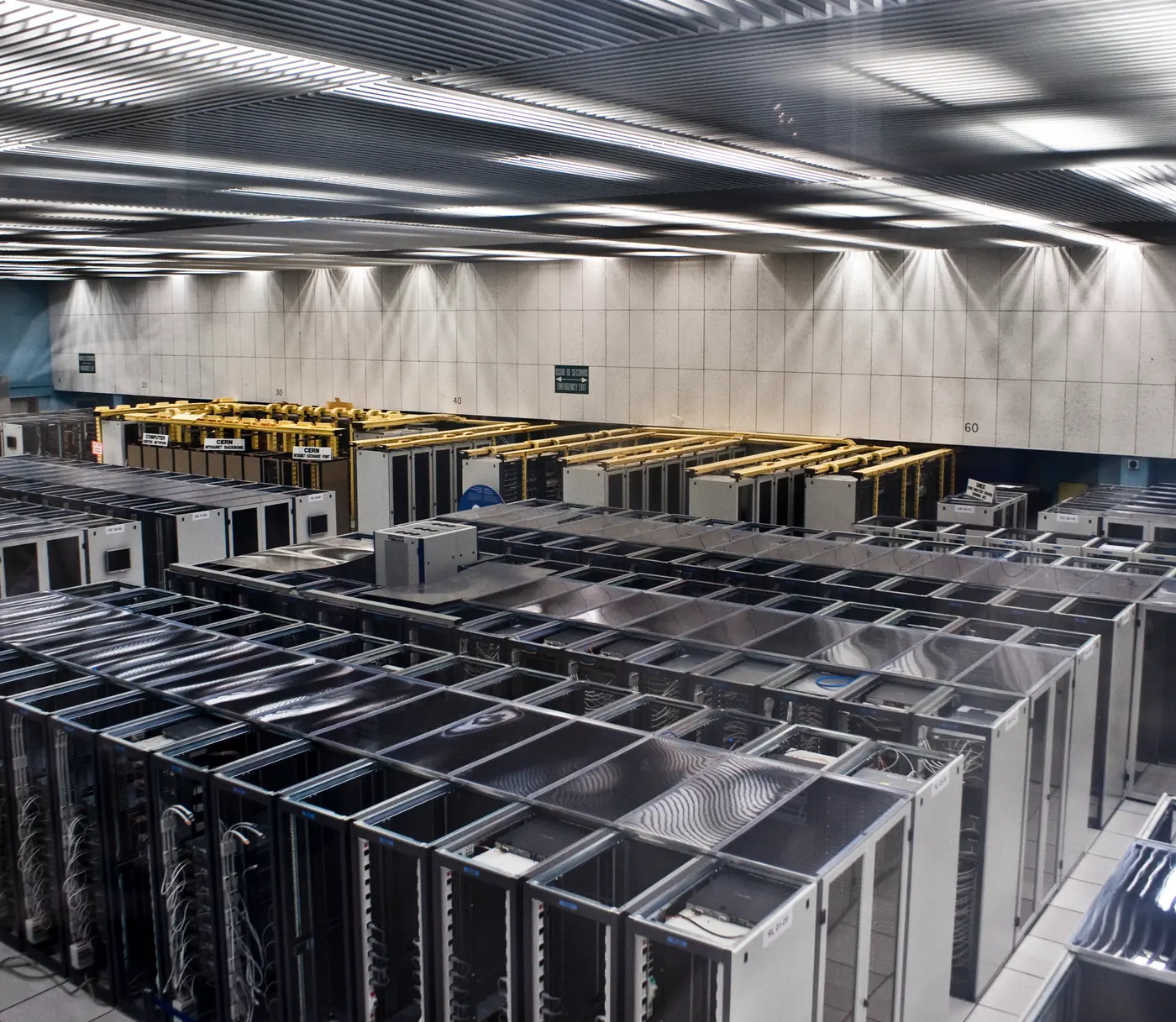A data hall seen from above, rows of server cabinets filling the floor under bright ceiling lights
